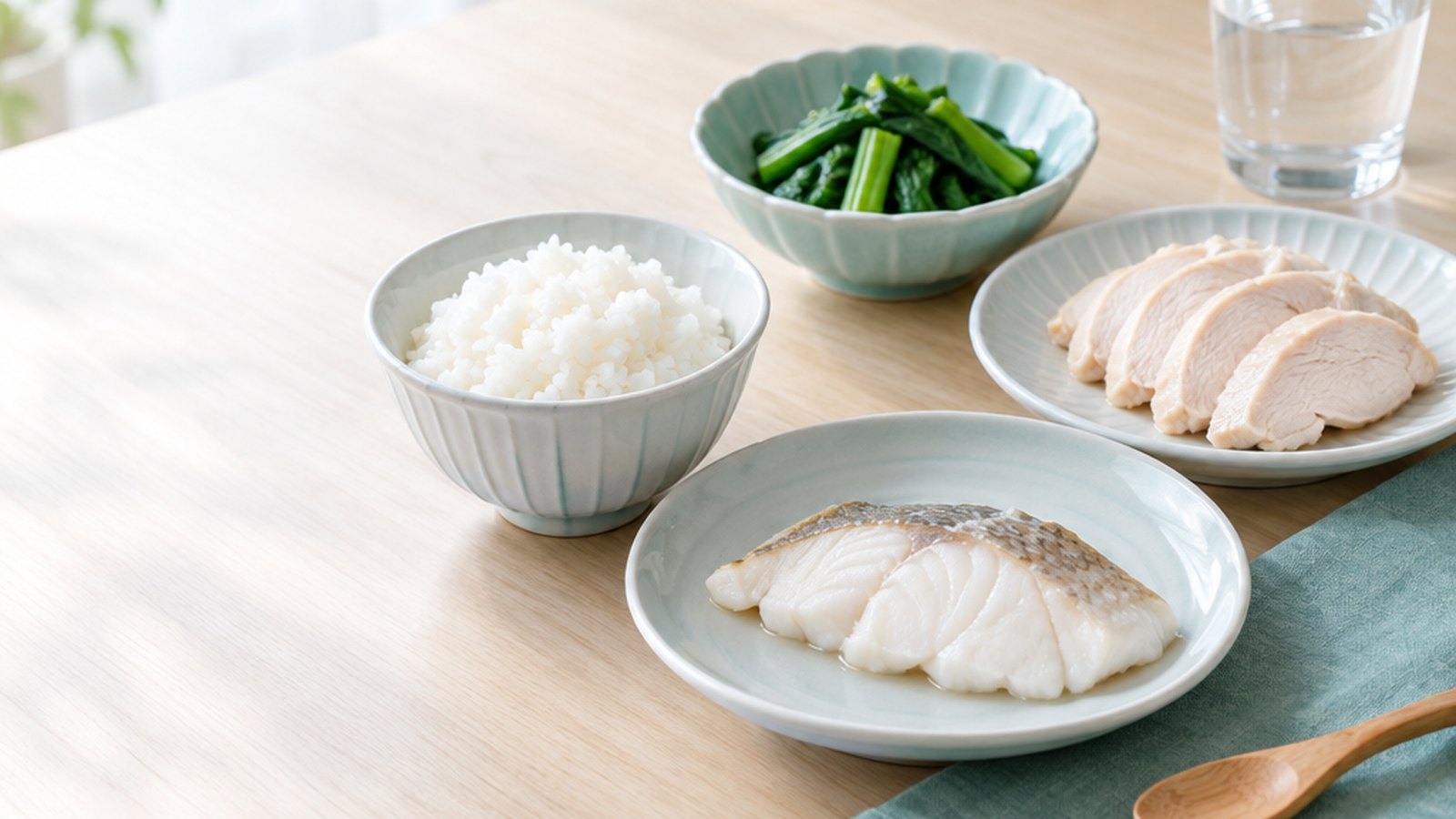 木質餐桌上擺放透析腎友的餐點:白飯、清蒸魚、水煮雞肉與汆燙青菜,以及一杯開水